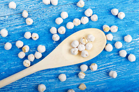 spilled chickpeas on a blue wooden background, lies next to wooden spoonの写真素材