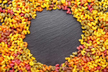 Multicolored pasta scattered on a black background, space for textの写真素材
