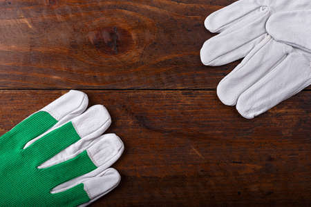 New and clean construction gloves on a wooden background, space for text, horizontal photoの写真素材