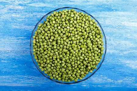 young peas in a clay plate on a wooden table. Horisontal photoの写真素材