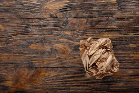 Crumpled paper on a wooden background, search for ideas, old rubbish, space for textの写真素材