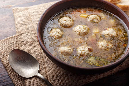 Homemade soup with meatballs on a napkin made of plain cloth, next to it lies a spoonの写真素材