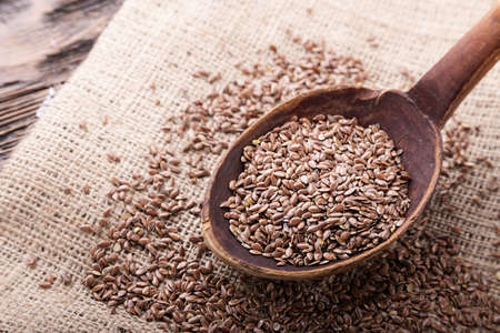 The seeds of flax are scattered on the table, on a linen napkin. Seeds in a wooden spoon. Horizontal photoの写真素材