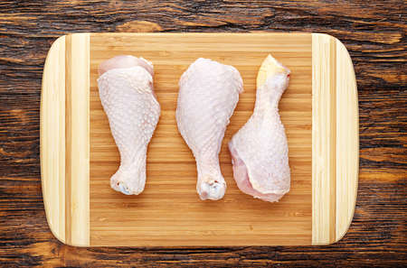 Raw chicken legs on a wooden board, top view, horizontal photoの写真素材