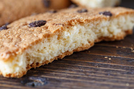 Pieces of cracked cookies close-up on a brown wooden background, horizontal photo
