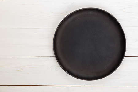 Empty round cast-iron frying pan for pizza or pie on a white wooden background, space for textの写真素材