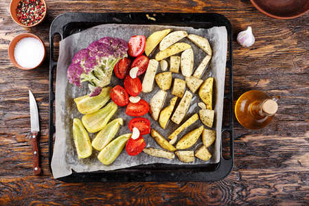 A vegetarian dinner in the oven. Different vegetables - tomatoes, peppers, cauliflower, potatoes are prepared for baking. view from aboveの写真素材