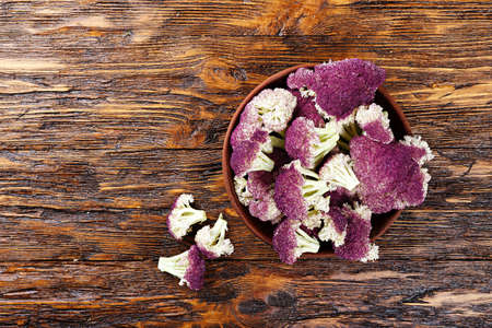 Cauliflower disassembled on inflorescences in a clay plate on a wooden tableの写真素材