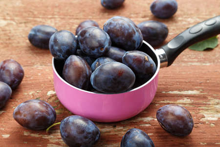 Ripe plums on a brown wooden table, healthy food, summer crop.の写真素材