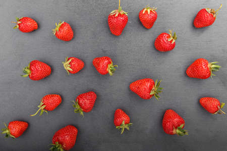 A ripe strawberry is scattered on the black background of a slate board. view from above. Space for textの写真素材