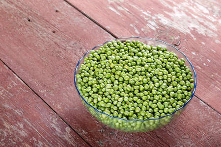 young peas in a transparent plate on an old wooden table. Horisontal photoの写真素材