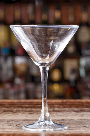 Empty cocktail glass on the background of the bar, space for text, night lifeの写真素材
