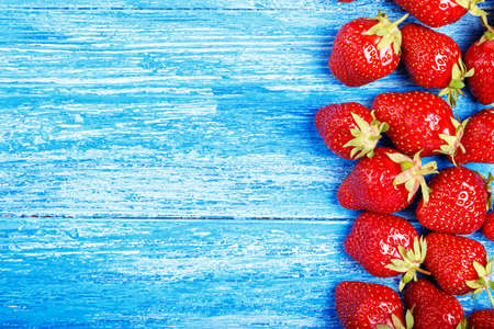 Fresh strawberries scattered on a blue wooden background, horizontal photo, space for textの写真素材