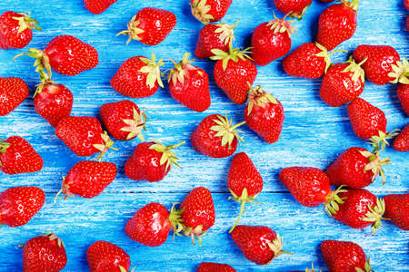 Ripe strawberry scattered on a wooden background, bright summer background, strawberry wallpaperの写真素材