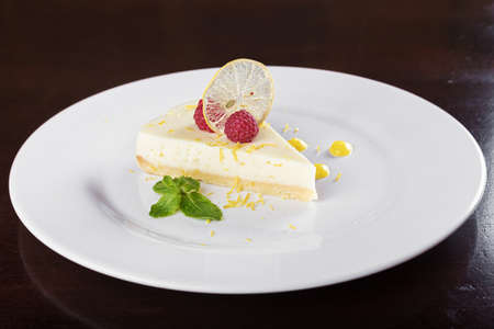 piece French lemon tart, garnished with fresh raspberries, mint and slice of lemonの写真素材