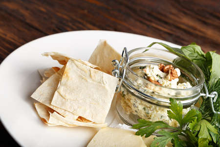 Cheese plate on a dark wooden table. Many kinds of cheese with basil, parsley, dill and pita on a plate. Horisontalの写真素材