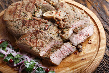 Medium rare grilled Beef steak Ribeye with onion on cutting board on dark wooden background.の写真素材