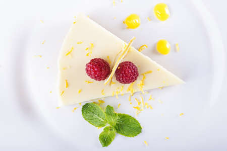 piece French lemon tart, garnished with fresh raspberries, mint and slice of lemonの写真素材