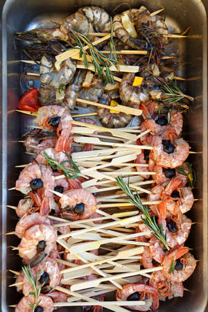 A lot of seafood on skewers, grilled shrimp in a metal container. Preparation for a banquetの写真素材