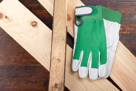Working gloves lie on a log, on a wooden background. The beginning of the carpenter's workの写真素材