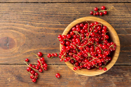 Red currant in a wooden plate, space for text, top view. country life