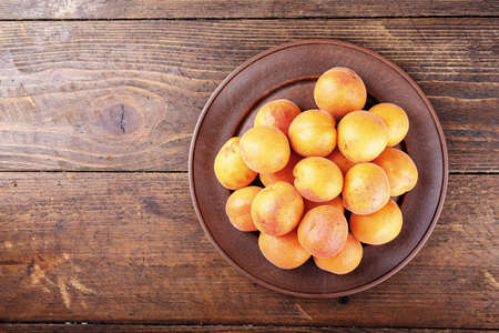 Ripe apricots on a clay plate, a summer harvest of useful fruit, space for textの写真素材