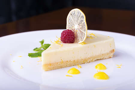 piece French lemon tart, garnished with fresh raspberries, mint and slice of lemonの写真素材