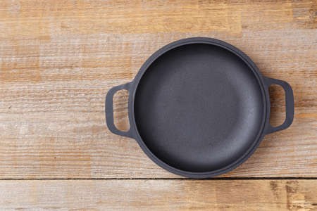 Empty frying pan view from above on an old wooden background, space for textの写真素材