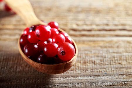 ripe cranberries in a wooden spoon on a wooden backgroundの写真素材