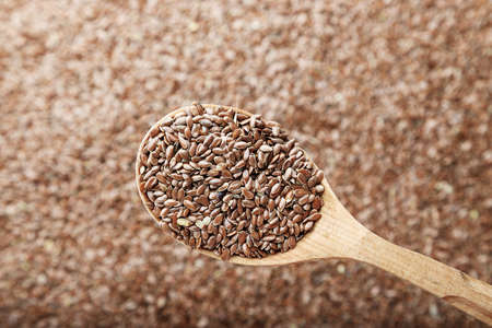 The seeds of flax are scattered on the table, on a linen napkin. Seeds in a wooden spoon. Horizontal photo. Space for textの写真素材