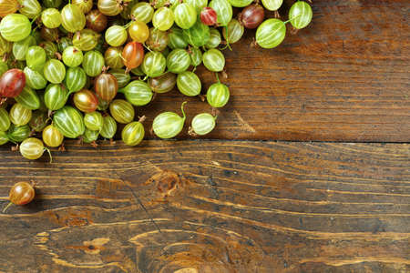 Gooseberries scattered on a wooden background, top view, space for textの写真素材