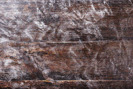 flour evenly scattered on a brown wooden background, space for text, culinary background