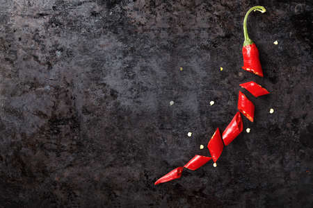 hot chili pepper cut, lined with pepper, on a black background