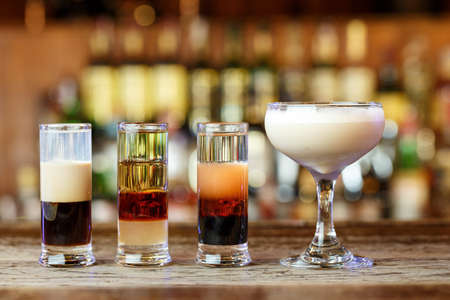 different club cocktails for men and women in different glasses stand on a bar counter on a blurred background of alcoholの写真素材
