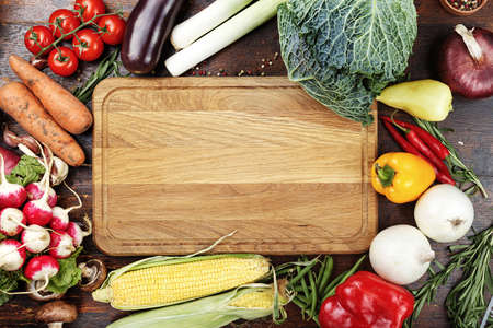 herbs and spices, vegetables and sauces on wooden background, in the middle of table is cutting bord like a space for textの写真素材