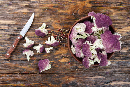 purple cauliflower and its cut inflorescences on a wooden background, near lies a knifeの写真素材