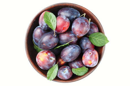 ripe plums in a wooden plate on a white background, isolated? top viewの写真素材