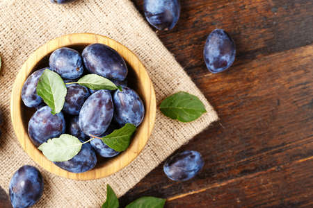 ripe plums on a wooden background, on a sackcloth napkin, top viewの写真素材
