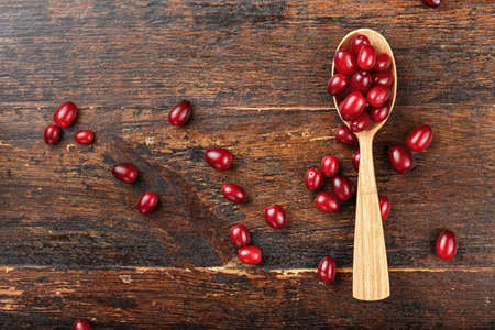 dogwood in a wooden spoon and scattered on a brown wooden surface, top viewの写真素材