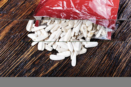 white sunflower seeds in open packaging, on wooden background With space for textの写真素材