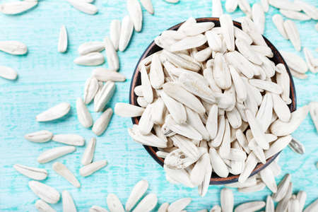 white sunflower seeds scattered on a  wooden background