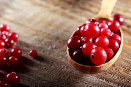ripe cranberries in a wooden spoon on a wooden backgroundの写真素材