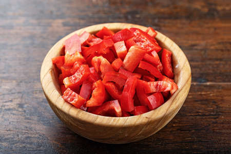 Sliced red bell pepper in a clay plate on a wooden backgroundの写真素材