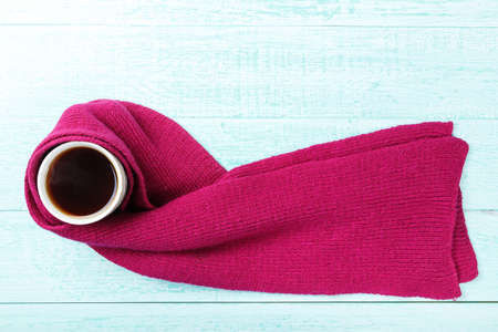 Cup of hot black tea with steam in  knitted scarf. view from above
