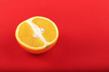Half an orange on a red background, a bright fruity background, space for textの写真素材