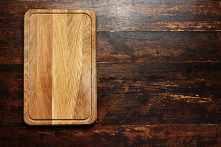 a new cutting board on a wooden background, top view, space for textの写真素材