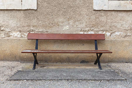 an empty wooden bench near an old cracked wallの写真素材