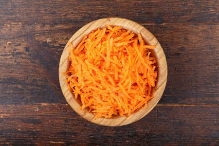 grated carrots in a plate, on a shabby wooden background, top viewの写真素材