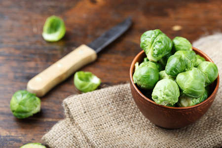 raw brussels sprouts in a plate on a wooden background, space for textの写真素材