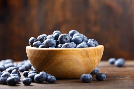 ripe organic bog whortleberry in a wooden plate on a wooden backgroundの写真素材